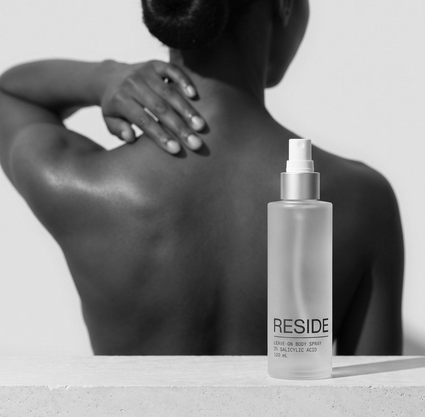 Reside bottle on a stone ledge, a bare back behind it